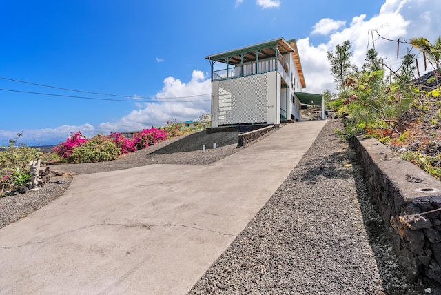view of property exterior with concrete driveway and a balcony