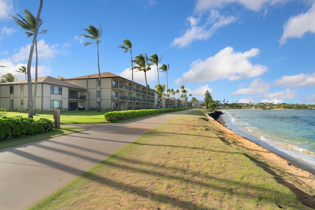 surrounding community featuring view of water and beach and a lawn
