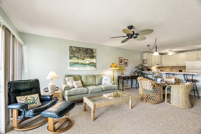 living area with ceiling fan, a textured ceiling, and carpet flooring