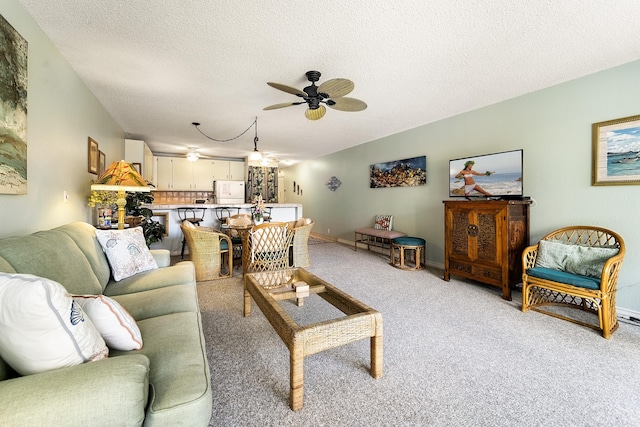 living room with ceiling fan, light carpet, a textured ceiling, and baseboards