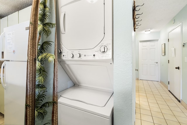 washroom with stacked washer / dryer, light tile patterned floors, and a textured ceiling
