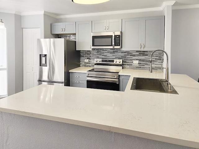 kitchen featuring appliances with stainless steel finishes, a sink, gray cabinets, crown molding, and backsplash