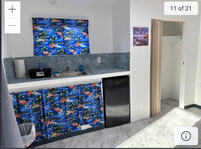 indoor wet bar featuring backsplash, fridge, and marble look tiles
