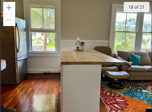 dining room with dark wood-type flooring, plenty of natural light, and wainscoting