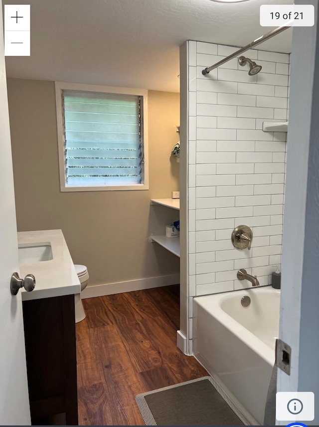 bathroom featuring wood finished floors, vanity, baseboards, toilet, and shower / bathtub combination