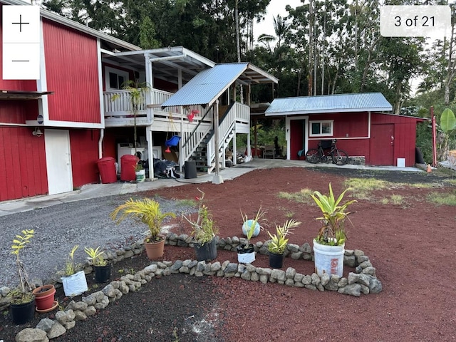 back of property with stairs, an outbuilding, and view of scattered trees