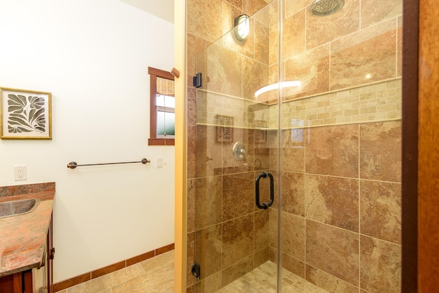 bathroom with a shower stall, vanity, and baseboards