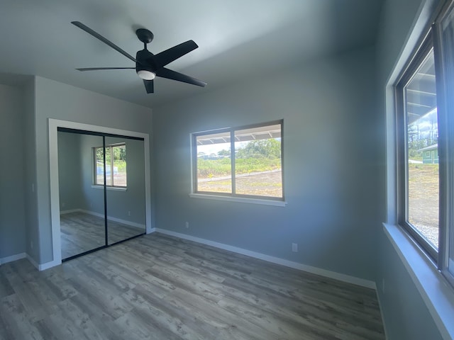 unfurnished bedroom featuring wood finished floors, baseboards, a closet, and ceiling fan