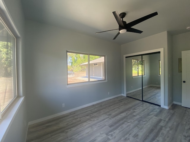 unfurnished bedroom with wood finished floors, a closet, baseboards, and a ceiling fan