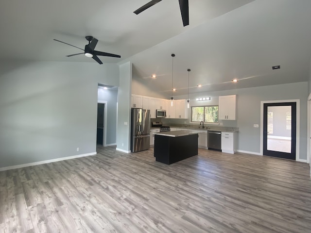 kitchen with appliances with stainless steel finishes, open floor plan, ceiling fan, and high vaulted ceiling