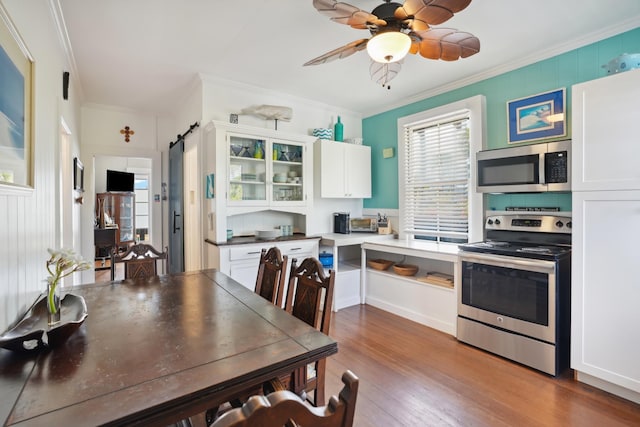 4-950 Kuhio Hwy, Kapaa, HI 96746 - kitchen featuring stainless steel appliances, crown molding, white cabinets, wood finished floors, and glass insert cabinets