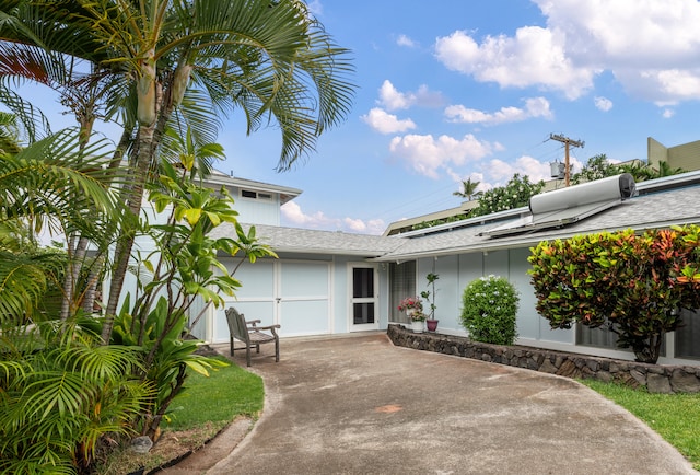 view of exterior entry with a shingled roof and concrete driveway