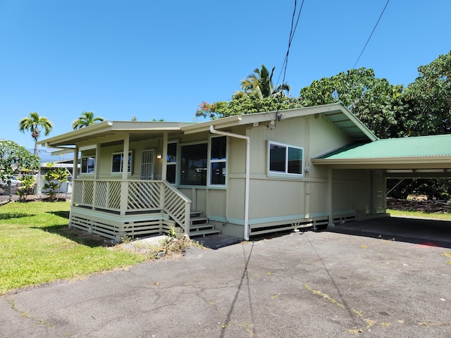 view of front of property with a carport, covered porch, asphalt driveway, and a front yard