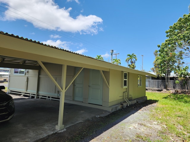 view of parking / parking lot with a carport and fence