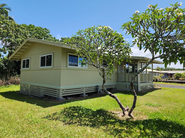 view of side of property featuring a lawn and covered porch