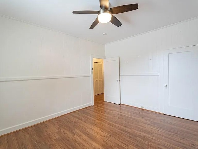 empty room with ceiling fan, wood finished floors, and baseboards
