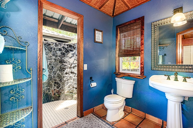 bathroom featuring toilet, tile patterned floors, baseboards, and a shower