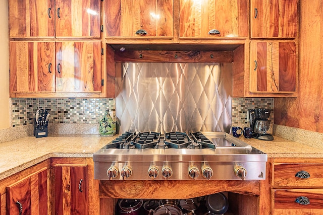 kitchen with stainless steel gas stovetop, tasteful backsplash, and brown cabinets