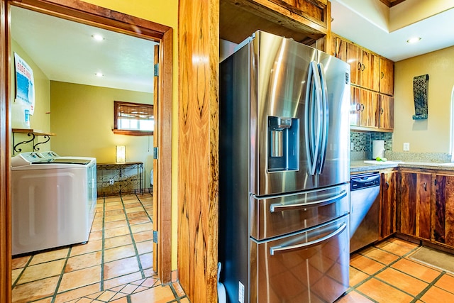 kitchen with stainless steel appliances, washer and dryer, light countertops, brown cabinets, and backsplash