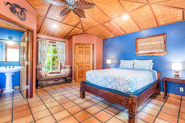 bedroom featuring vaulted ceiling, light tile patterned floors, and a textured wall
