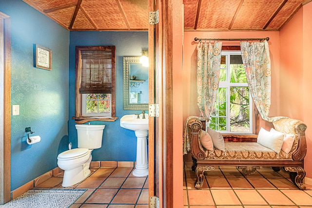 bathroom featuring toilet, tile patterned floors, wood ceiling, a textured wall, and baseboards