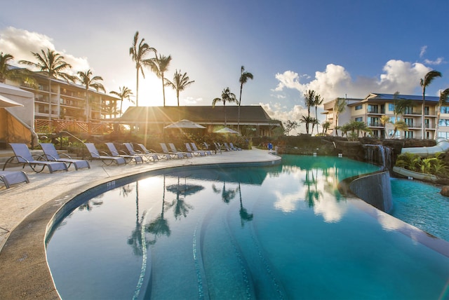 pool at dusk featuring a community pool and a patio area