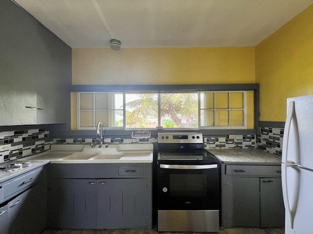 kitchen featuring electric stove, freestanding refrigerator, backsplash, and gray cabinetry