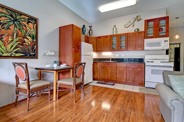 355 Kalanianaole St Unit 119, Hilo, HI 96720 - kitchen with white appliances, a sink, dark countertops, glass insert cabinets, and light wood-style floors