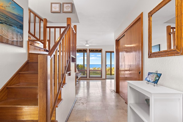 staircase with a ceiling fan and a textured wall