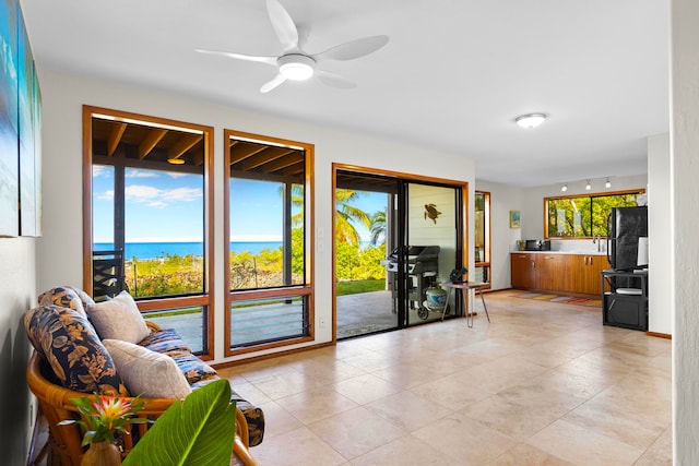 living area with a water view and a ceiling fan