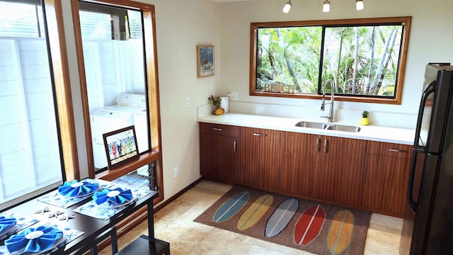 kitchen with freestanding refrigerator, a sink, light countertops, and washer and clothes dryer