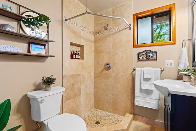full bath with a tile shower, toilet, and vanity