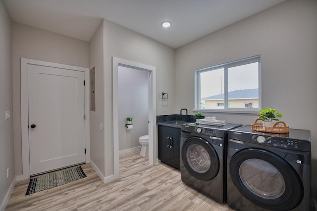 laundry area featuring washer and clothes dryer, light wood-type flooring, baseboards, and electric panel