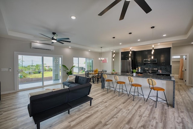 living room featuring a tray ceiling, a ceiling fan, an AC wall unit, and recessed lighting