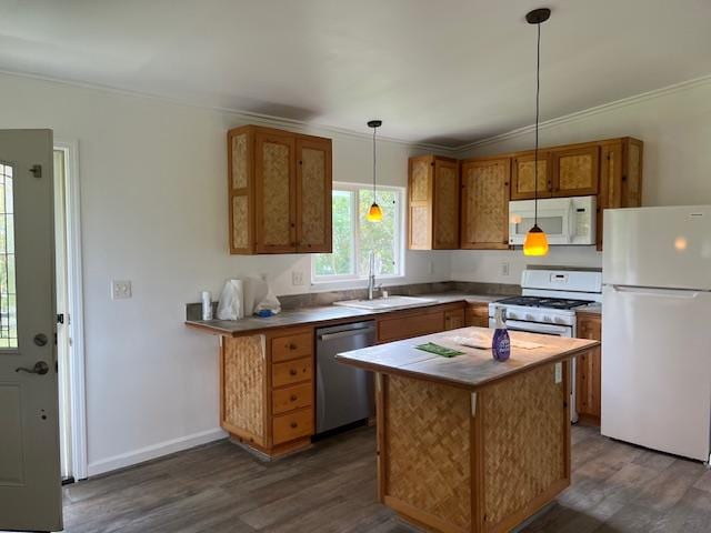 kitchen featuring white appliances, a sink, crown molding, dark wood-type flooring, and brown cabinetry