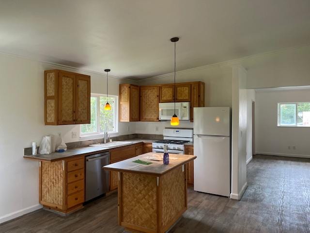 kitchen featuring white appliances, a sink, dark wood-type flooring, pendant lighting, and brown cabinetry