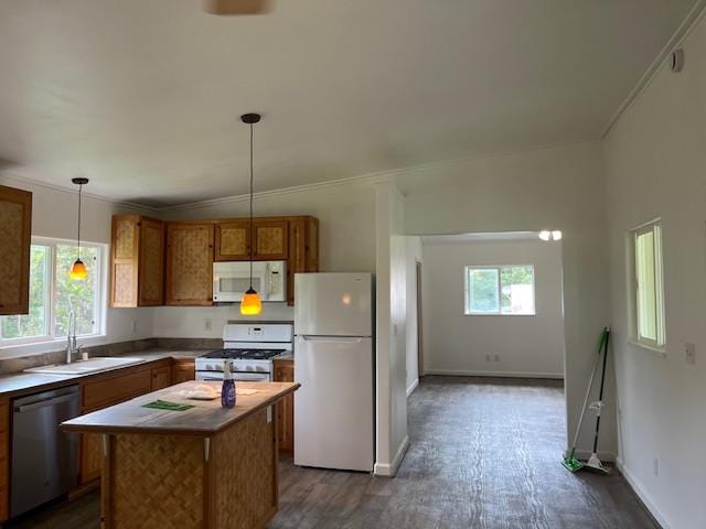 kitchen with white appliances, a sink, dark wood-style floors, brown cabinetry, and a center island