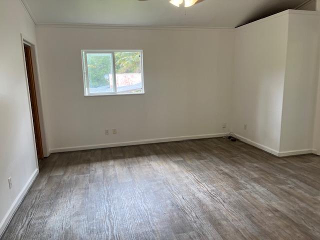spare room with wood finished floors, ceiling fan, baseboards, and ornamental molding