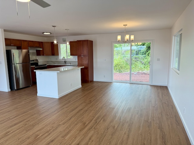 kitchen with appliances with stainless steel finishes, a sink, light wood-style flooring, light countertops, and baseboards