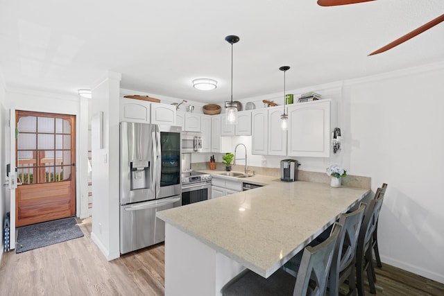 3411 Wilcox Rd Unit B 21, Lihue, HI 96766 - kitchen featuring appliances with stainless steel finishes, a sink, a peninsula, crown molding, and a breakfast bar area
