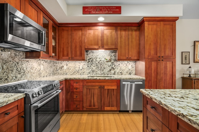 2611 Kiahuna Plantation Dr Unit 13D, Koloa, HI 96756 - kitchen with stainless steel appliances, a sink, light wood finished floors, light stone counters, and glass insert cabinets
