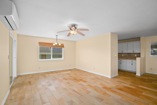 5372 Kumole St, Kapaa, HI 96746 - unfurnished living room featuring a wall mounted air conditioner, a ceiling fan, light wood-style floors, a chandelier, and baseboards