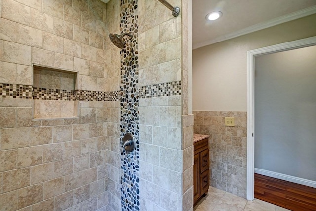 bathroom with crown molding, tile flooring, tiled shower, vanity, and tile walls