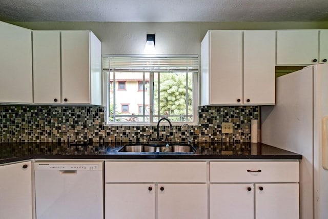 kitchen featuring tasteful backsplash, white appliances, white cabinetry, dark stone countertops, and sink