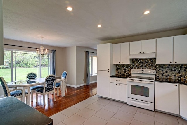 kitchen with light tile flooring, white range with electric cooktop, a notable chandelier, decorative light fixtures, and white cabinets