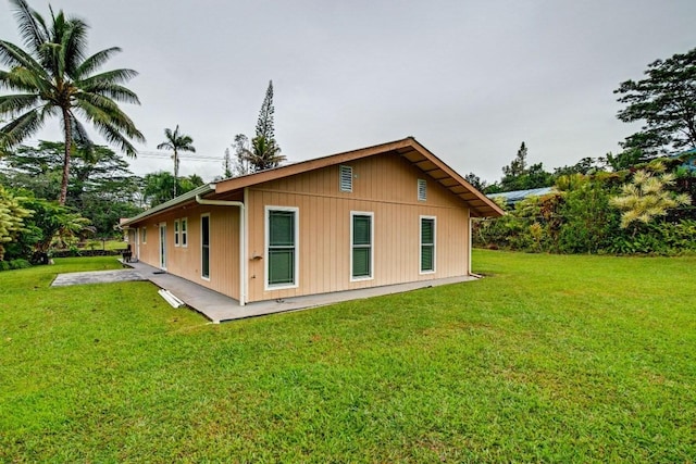 view of side of property featuring a patio and a lawn