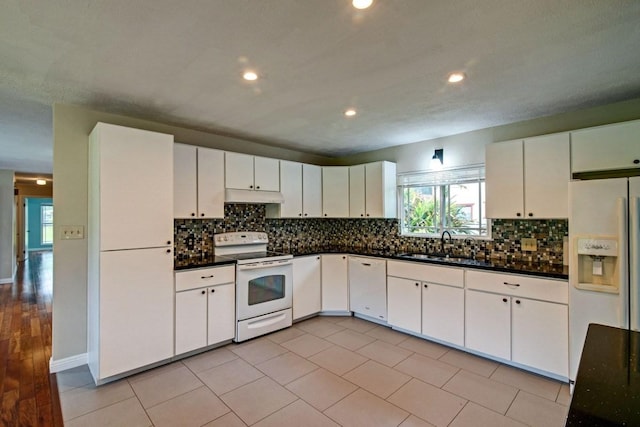 kitchen featuring white appliances, white cabinets, backsplash, and light tile flooring