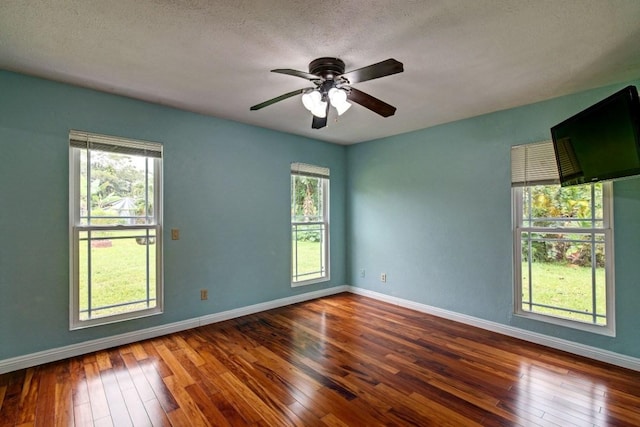 unfurnished room featuring ceiling fan, dark hardwood / wood-style floors, and a wealth of natural light