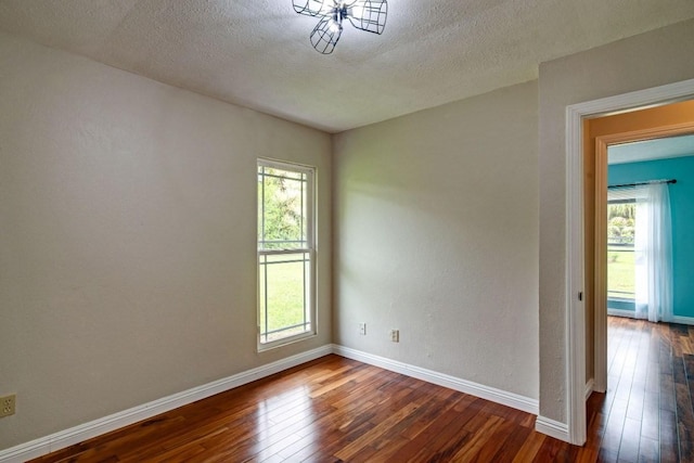 spare room with a healthy amount of sunlight, dark wood-type flooring, and a textured ceiling