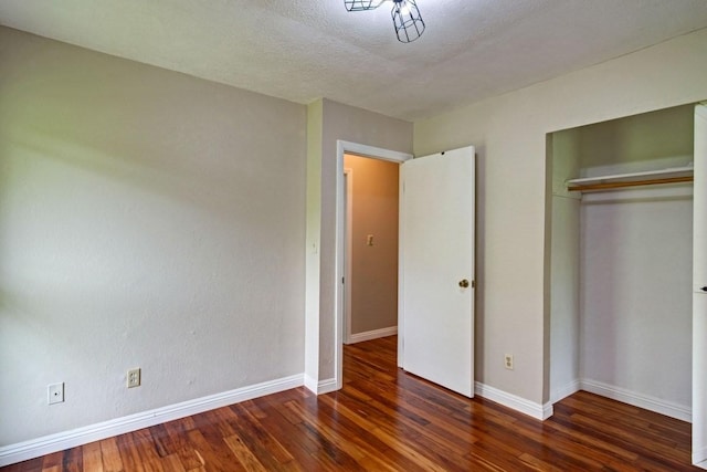 unfurnished bedroom featuring a closet, a textured ceiling, and dark hardwood / wood-style floors